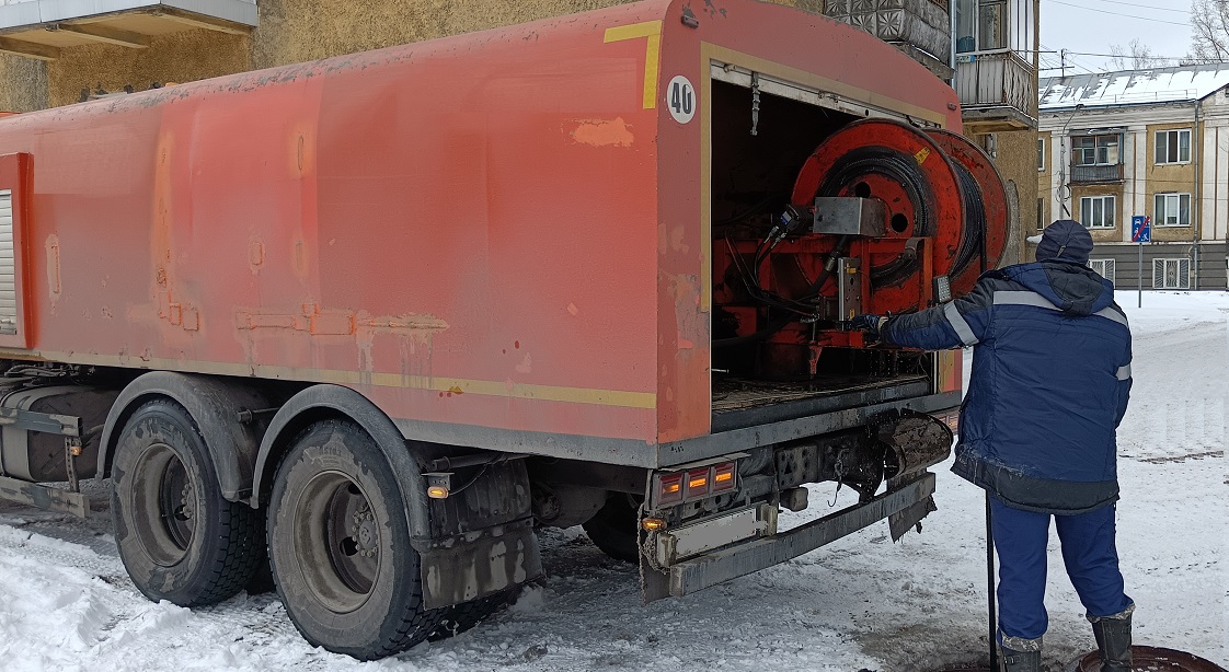 Каналопромывочная машина и работник прочищают засор в канализационной системе в Ордынском