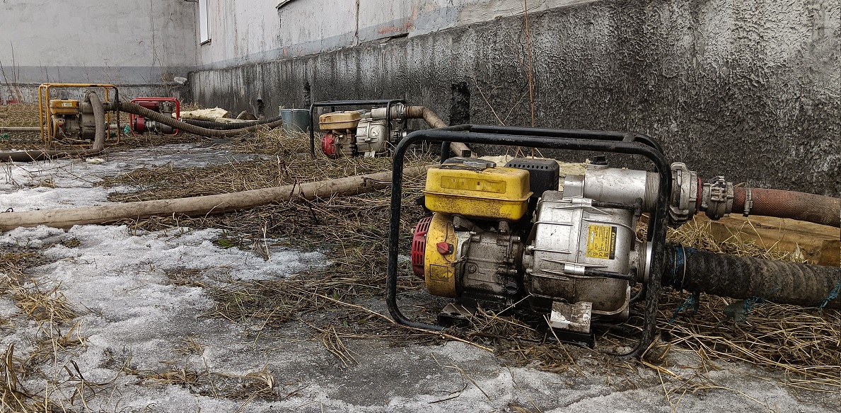 Откачка мотопомпами талой воды из подвала дома в Новосибирской области